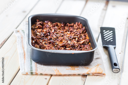 Homemade Mashed Sweet Potato Casserole with Caramelized Pecans on Light White Wooden Background photo