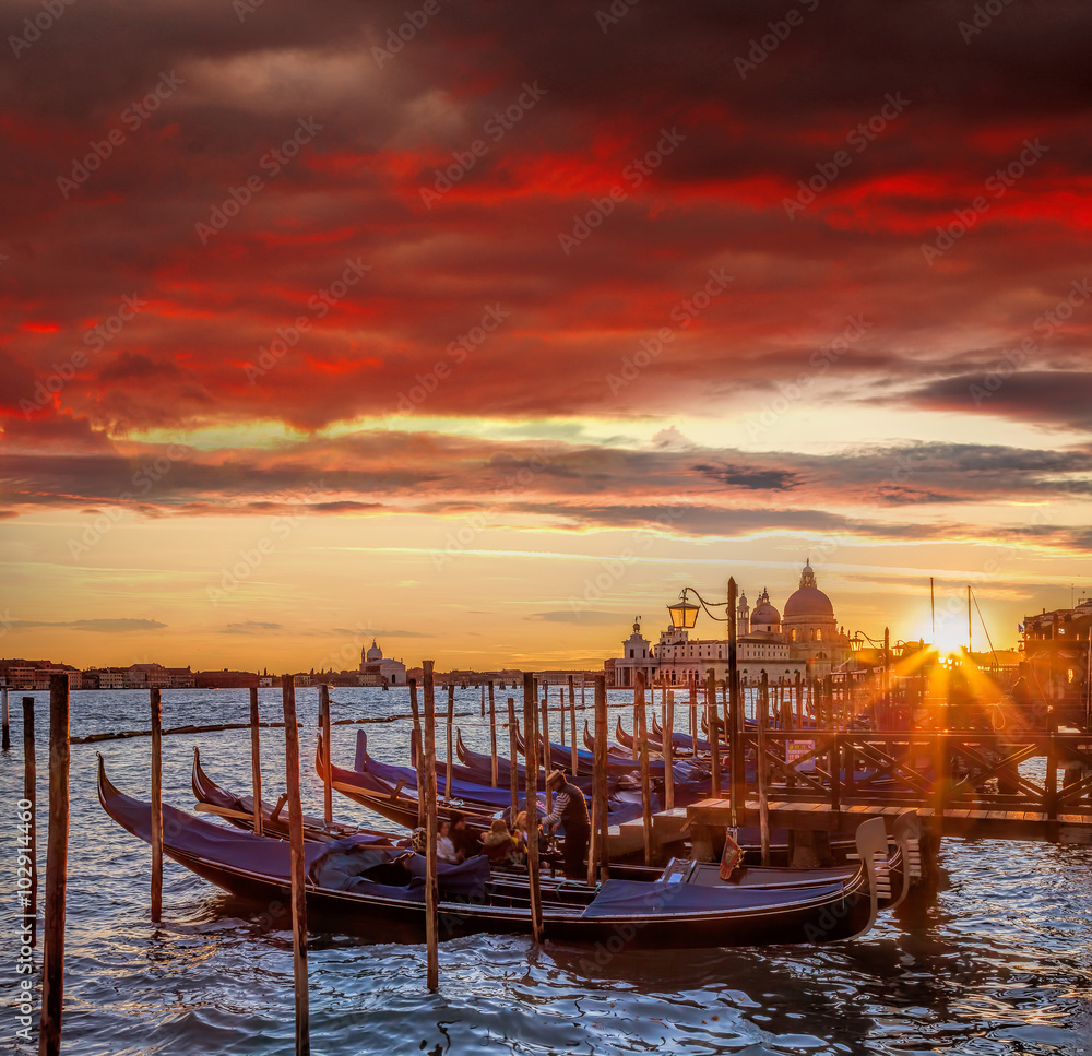 Venice with gondolas against colorful sunset in Italy