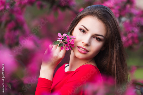 Happy beautiful young woman in spring blossom park. 