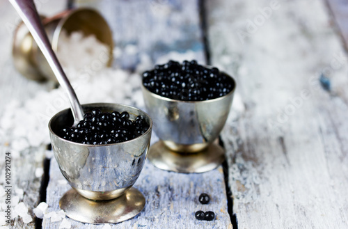 Black caviar in small round metal tin on ice. Selective focus