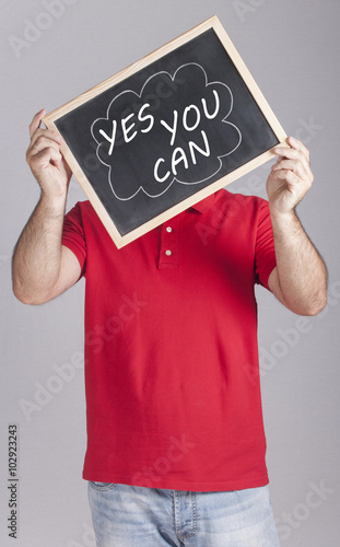 Man holding Yes You Can message written on a blackboard photo