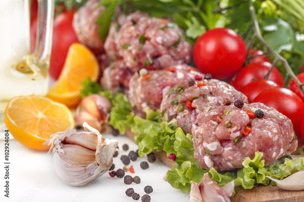 Fresh meatballs with various vegetables on a white background