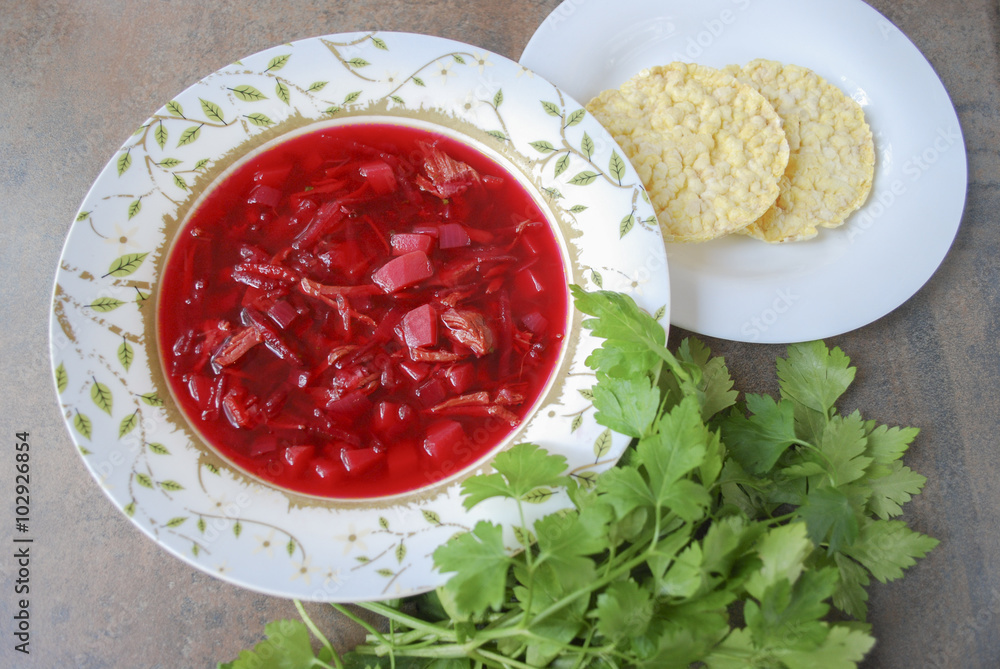 Beetroot soup in plate with parsley and corn crackers on brown background. Finished dish. Ukrainian and Russian cuisine. Beetroot soup in plate with parsley and corn crackers on brown background. Finished dish. Ukrainian and Russian cuisine.