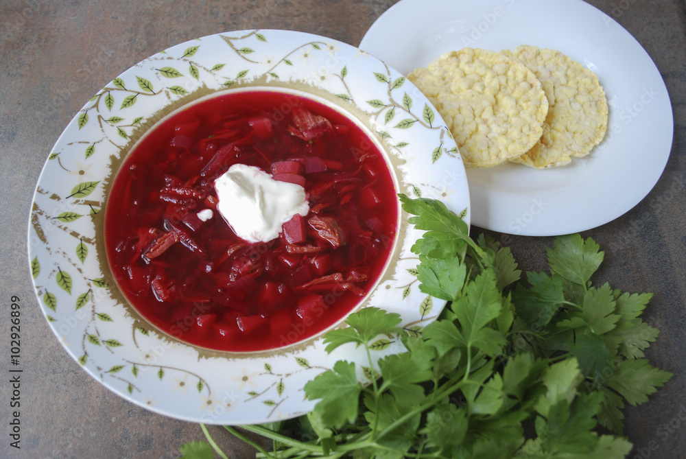 Beetroot soup in plate with parsley and corn crackers on brown background. Finished dish. Ukrainian and Russian cuisine. Beetroot soup in plate with parsley and corn crackers on brown background. Finished dish. Ukrainian and Russian cuisine.