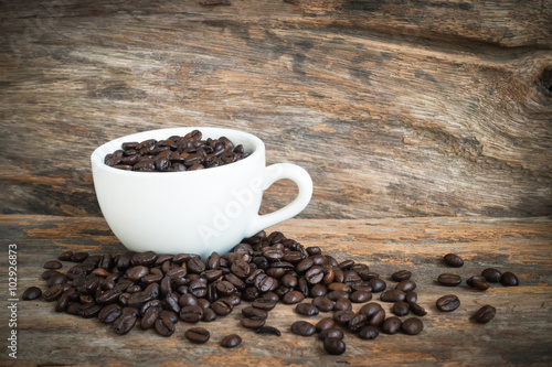 white coffee cup and coffee bean on wood background