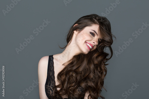 Smiling brunette woman with long hair. Waves Curls Hairstyle. Hair Salon. Model with shiny hair.