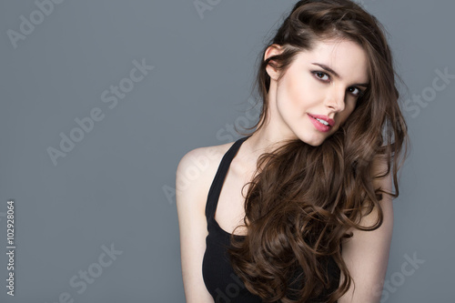 Beautiful woman model brunette with long curled hair.