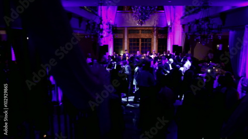 Group of silhouetted people dancing in a dark banquet hall for a wedding reception.