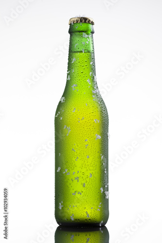 Bottle of ice cold beer with ice and drops