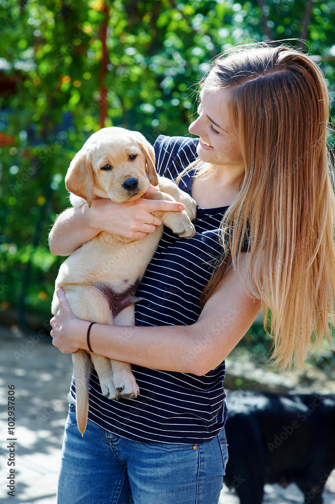 Portrait of Young woman holding on hands puppy Labrador Portrait of Young woman holding on hands puppy Labrador