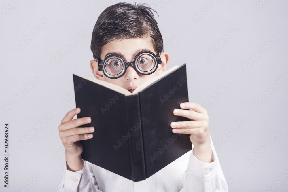 Funny nerdy little boy reacts while reading a book
