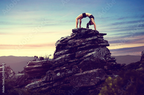 Woman does gymnastics on a rock photo