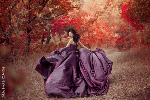 Foto Lady in luxury lush purple dress runs in red wood ,fantastic shot, fairytale girl princess walking in autumn forest, fashionable toning, creative colors