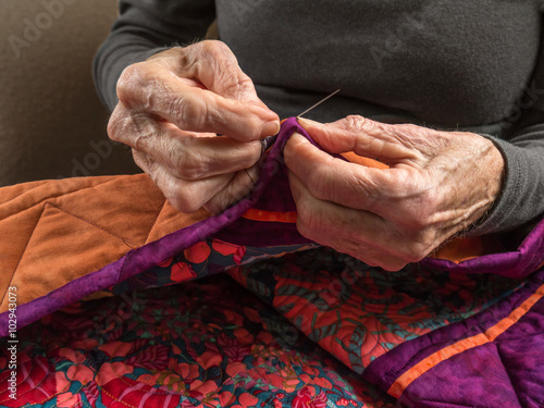 A Senior Woman Expertly Stitches the Binding Onto Her Quilt
