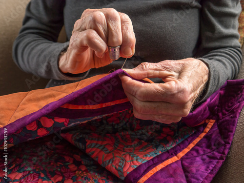 A Senior Woman Expertly Stitches the Binding Onto Her Quilt