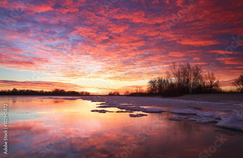 Beautiful colorful winter landscape with frozen lake and sunset