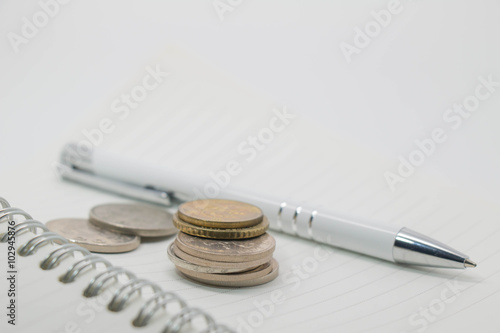 coins on book and pen business finance home concepts
