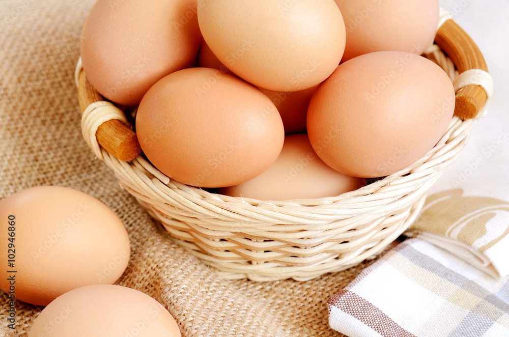 Wicker basket with eggs on a linen tablecloth Wicker basket with eggs on a linen tablecloth