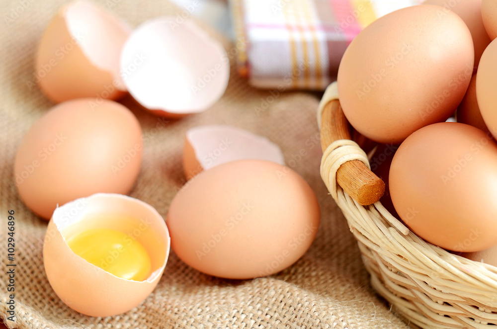 Wicker basket with eggs and raw egg on a linen tablecloth Wicker basket with eggs and raw egg on a linen tablecloth