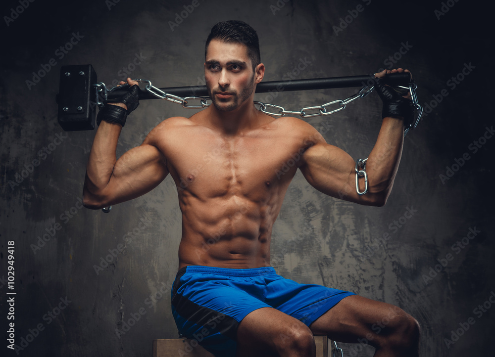 Shirtless muscular man holding a big hammer.