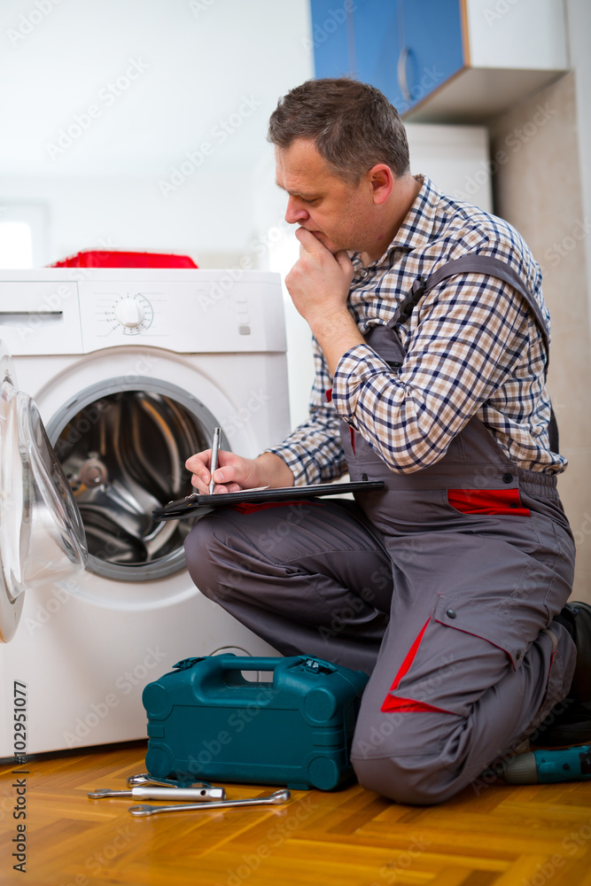 Obraz premium Repairman is repairing a washing machine on the white background. Entering malfunction