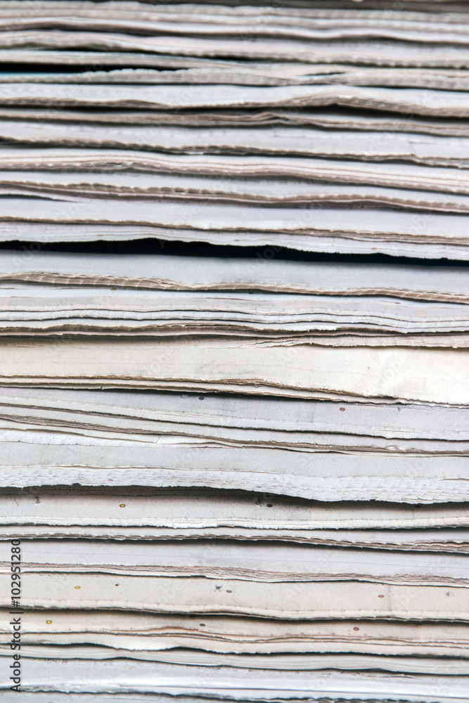 View of a pile of newspapers stacked isolated on a white background. View of a pile of newspapers stacked isolated on a white background.