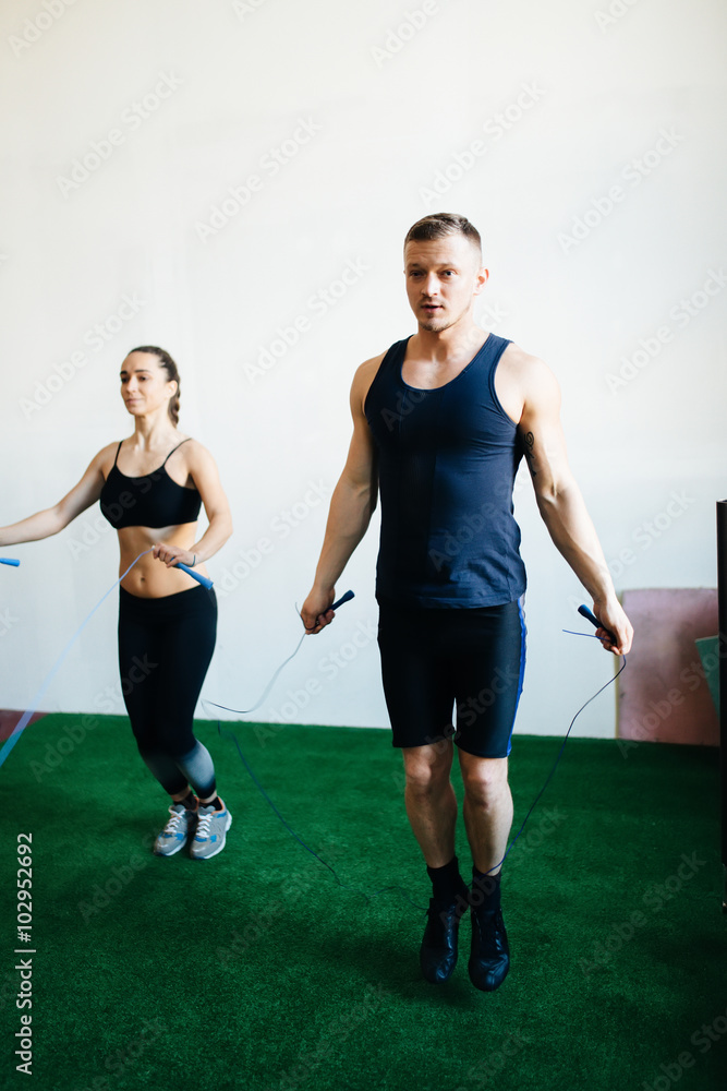 Two people jumping on a skipping rope in gym Two people jumping on a skipping rope in gym