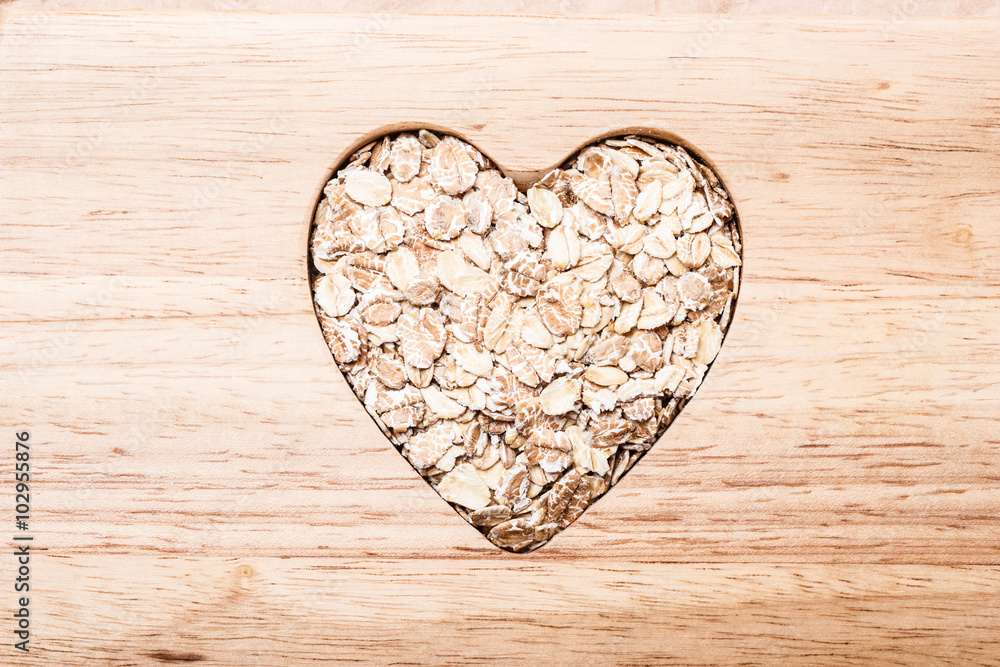 Obraz premium Oat cereal heart shaped on wooden surface.