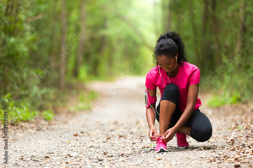 Fotografie African american woman runner tightening shoe lace - Fitness, pe