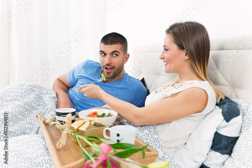 Young couple enjoying romantic breakfast in bed