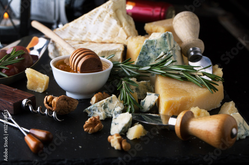 Delicious cheeses on a board with honey, nuts and wine