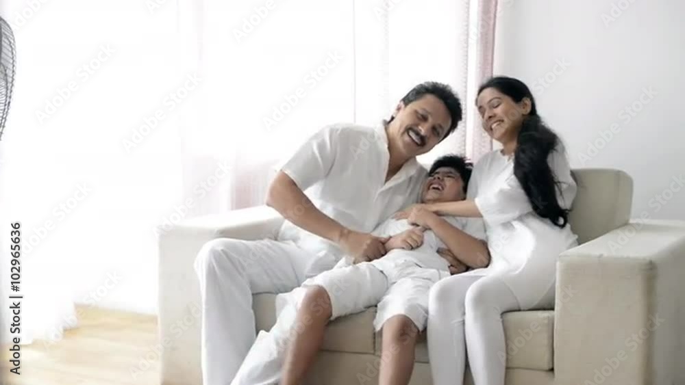 Pan shot of a couple enjoying with their son on a couch Pan shot of a couple enjoying with their son on a couch