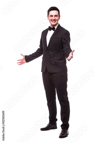 Cheerful young man in suit welcome sign and smiling while standing against white background.Showman concept.