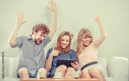 Successful happy friends with tablet at home.