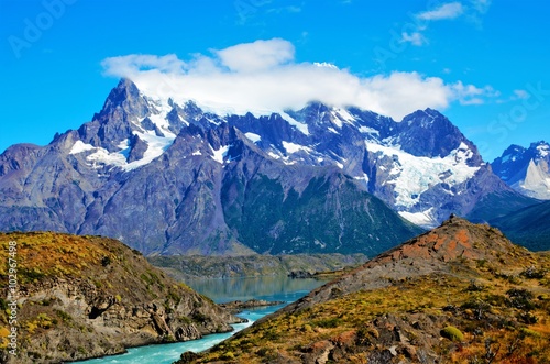 SALTO GRANDE, TORRES DEL PAINE NATIONAL PARK, CHILE - FEBRUARY, 5, 2016: Waterfall between green and brown hills, in the background snow covered mountain