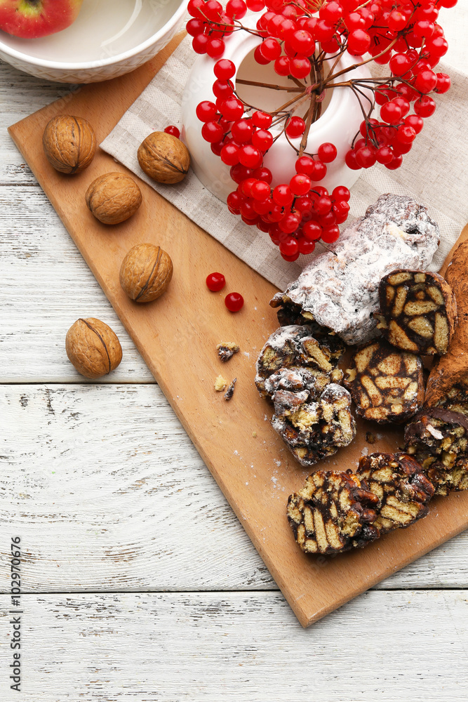 Chocolate salami with nuts and red berries over wooden background
