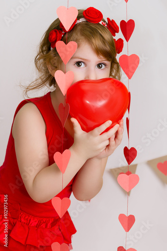 Sweet child lgirl playing with red heart shaped balloon photo