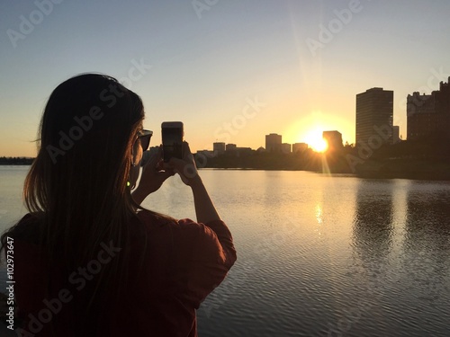female taking a photo of oakland, CA with a smartphone