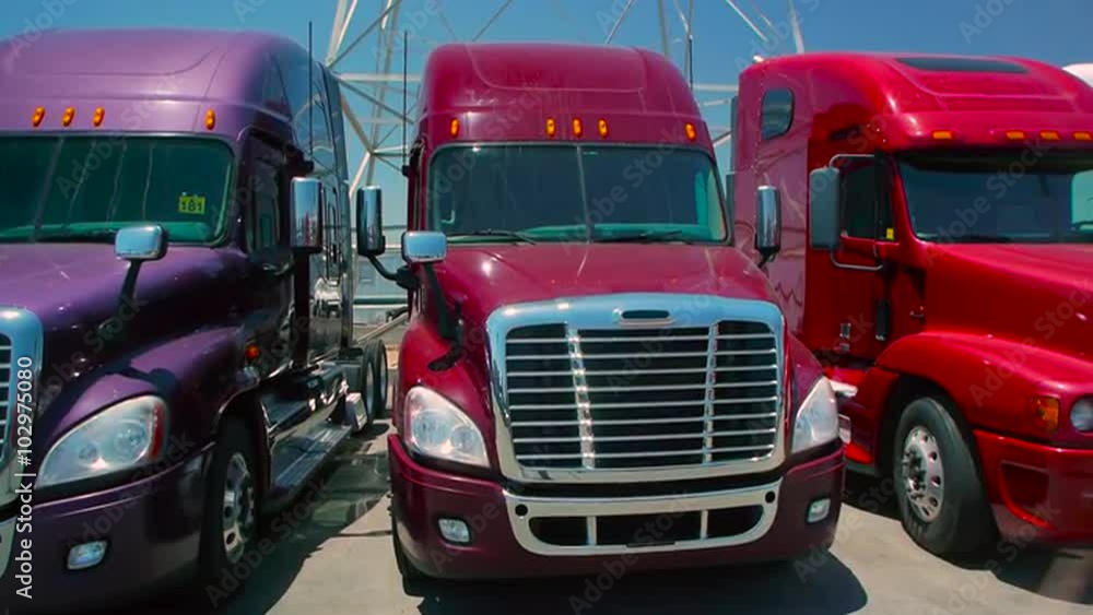 Slow pan down from electric tower to three freight liner trucks parked outdoors Slow pan down from electric tower to three freight liner trucks parked outdoors