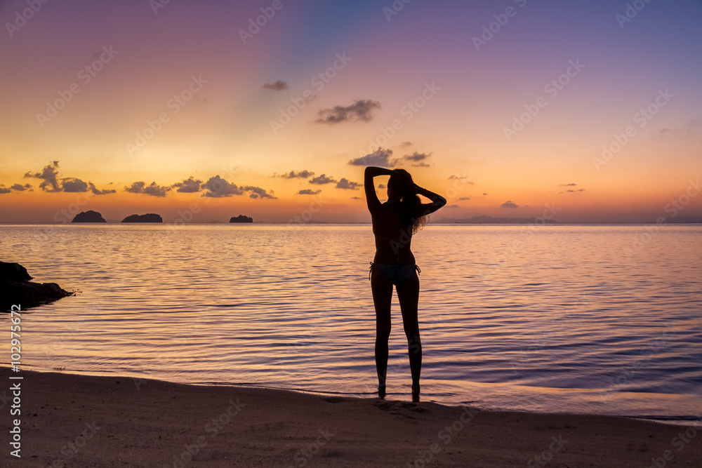Young woman stay on the beach by the sea and watching the sunset on a tropical island Koh Samui, Thailand
