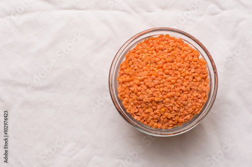 Red lentils in a glass dish on a white tablecloth (top down)