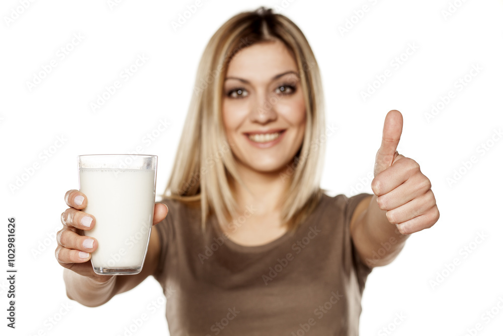 happy young woman holding a glass of milk and showing thumbs up happy young woman holding a glass of milk and showing thumbs up