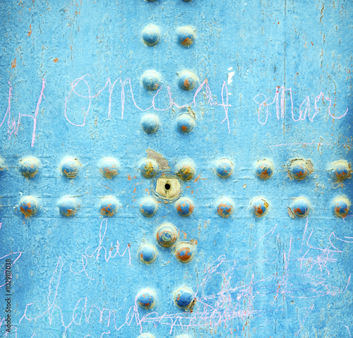 dirty stripped paint in the blue wood door and rusty nail photo