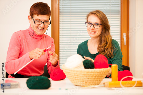 Women knitting with red wool. Eldery woman transfering her knowl photo