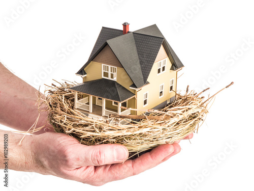 A man holds a birds nest with a miniature home inside