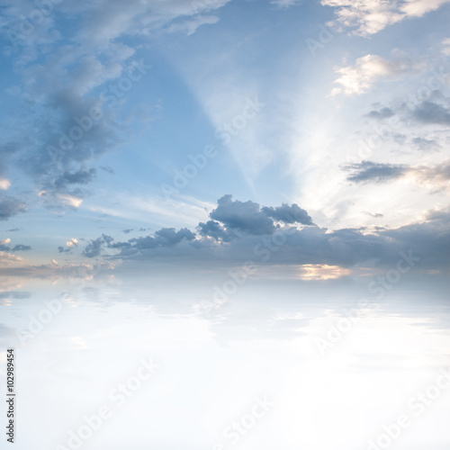 Sunset over ocean, clouds in blue sky