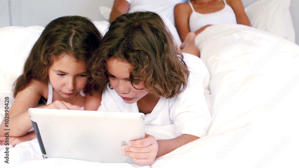 Cute siblings using tablet on their parents bed Cute siblings using tablet on their parents bed
