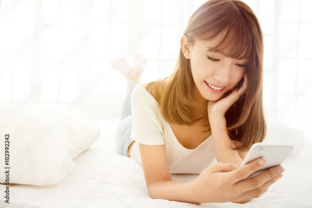 Young smile woman reading smart phone on bed Young smile woman reading smart phone on bed