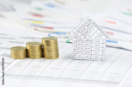 Close up house and step gold coins have blur paperwork