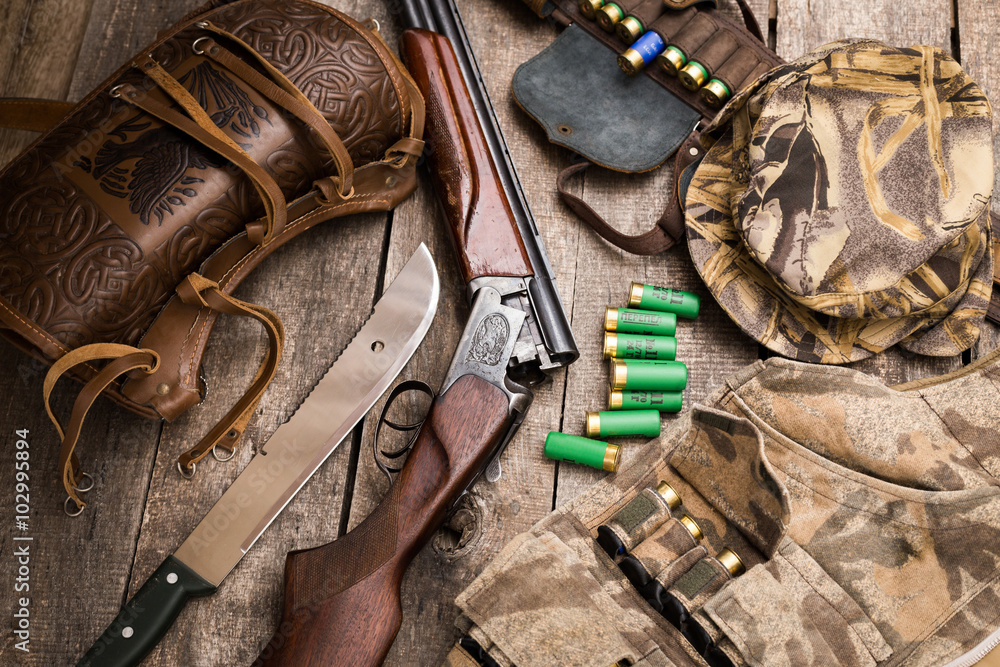Hunting shotgun and ammunition on wooden background